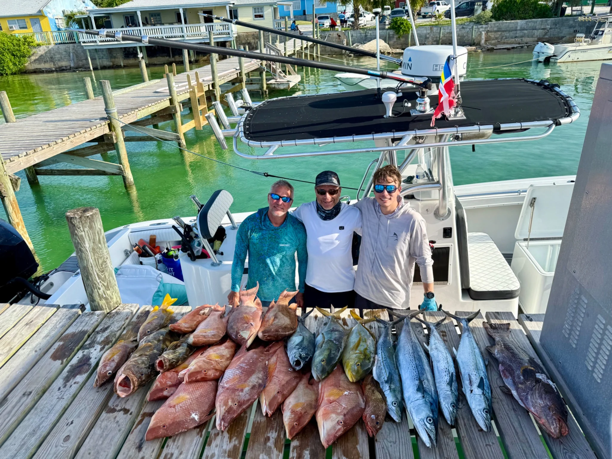 Two people displaying the day’s catch beside a dock