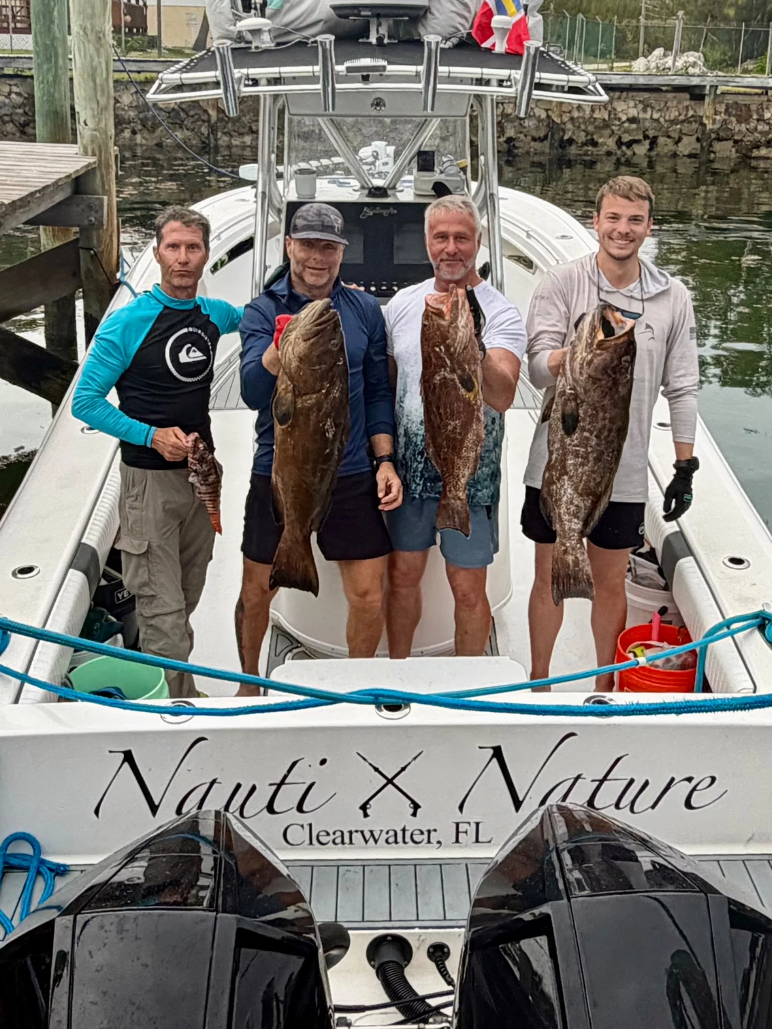A group aboard Nauti Nature gathered around a large grouper catch